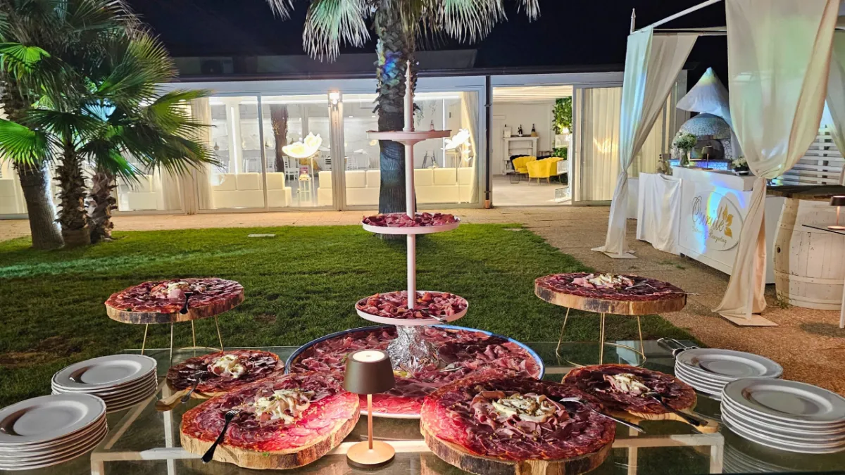 Giardino allestito di sera con tavoli e fiori rossi